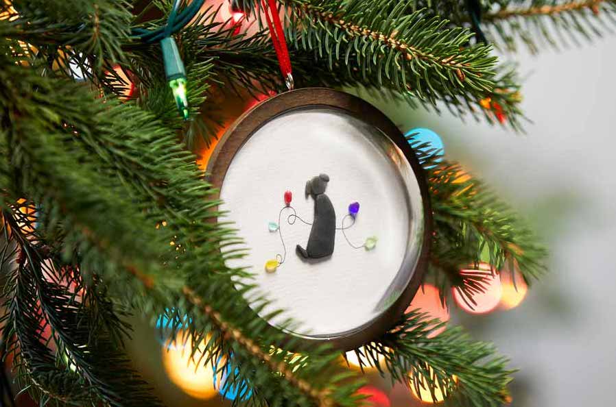 Handcrafted dog ornament on a Christmas tree.