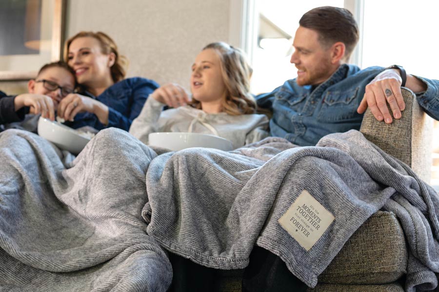 Family sitting on the couch with a blanket.